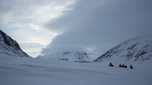 Team with pulkas making a break between the mountains, Greenland